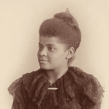 Archival sepia photo of trailblazing African American journalist and organizer, Ida B. Wells-Barnett. Wells-Barnett is a 20th century Black woman wearing a ruffled dress. Her hair is styled in an updo.