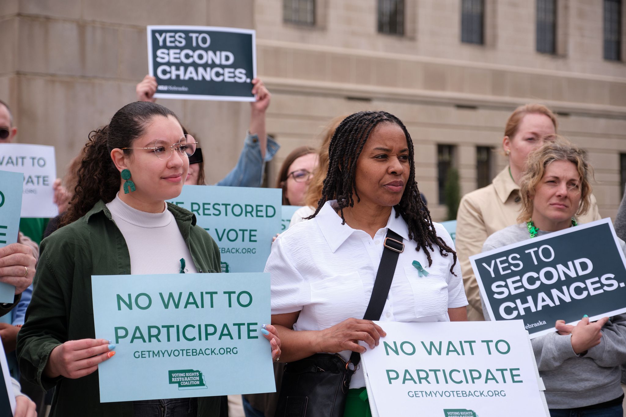 Nebraska advocates stand outside the Nebraska capital building holding signs that read "No wait to participate" and "Yes to second chances."